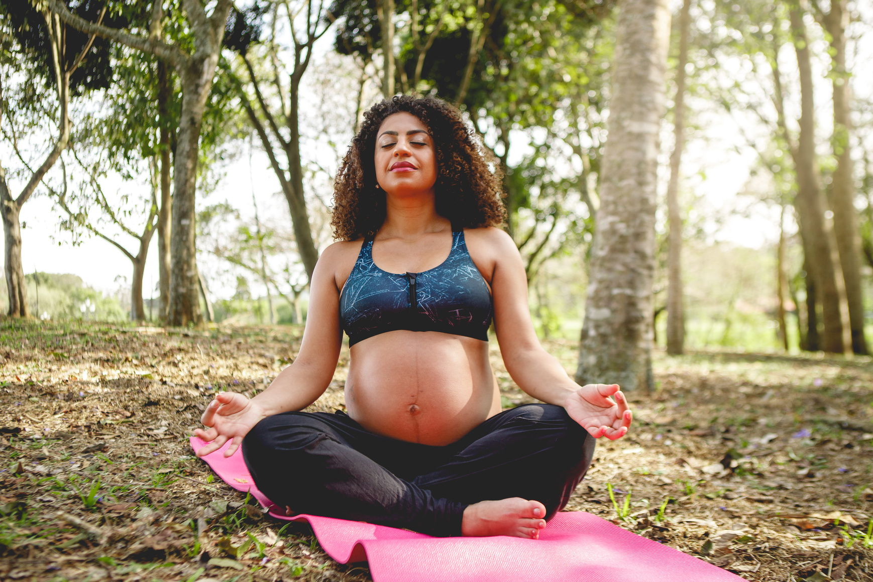 pregnant black woman doing yoga outdoors