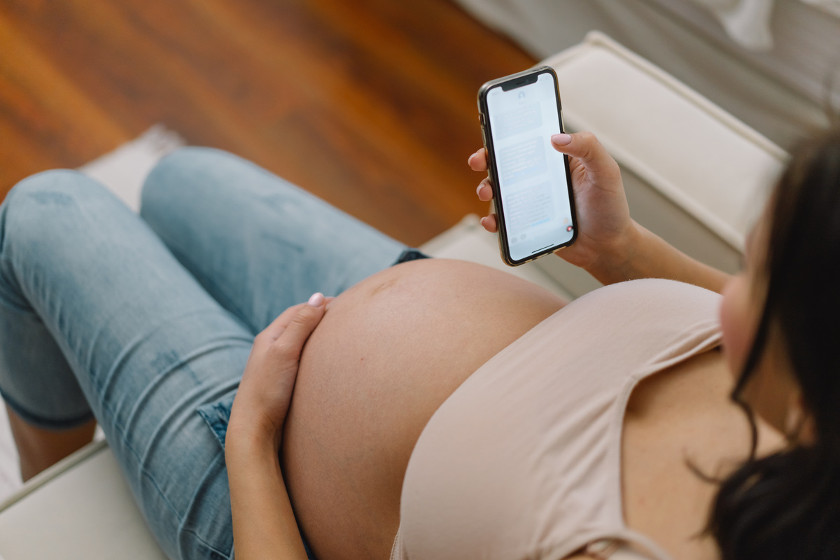 Happy charming pregnant woman using mobile phone. Pregnant Woman.